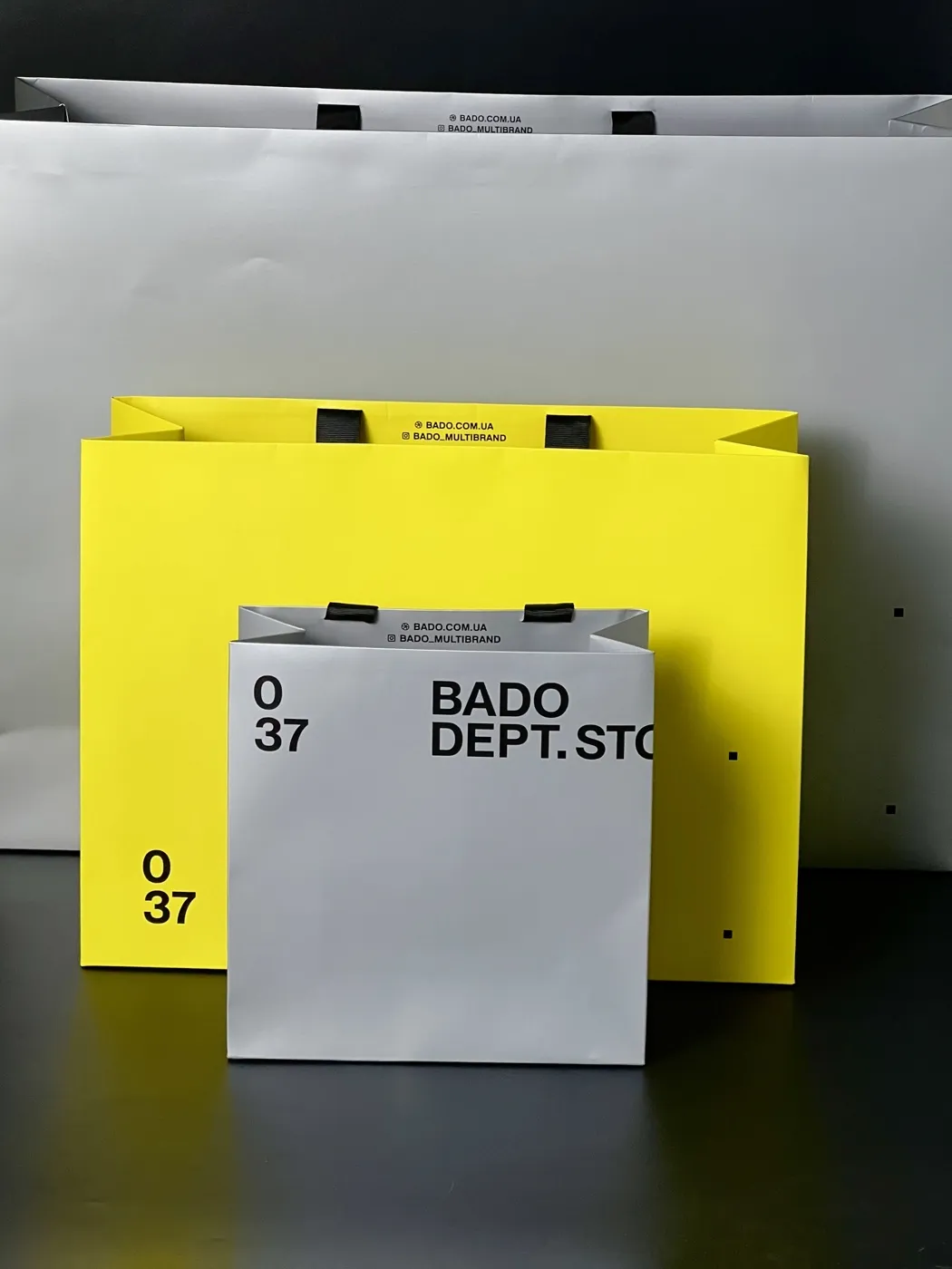 Брендовані пакети BADO Dept. Store: білий і жовтий паперовий пакет з логотипом