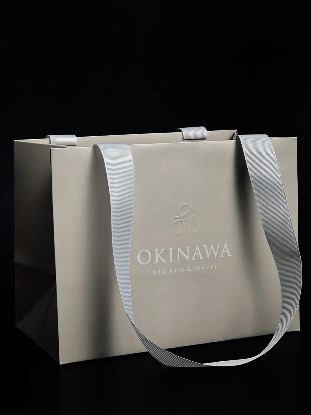 Сірий паперовий пакет з логотипом OKINAWA і атласними ручками